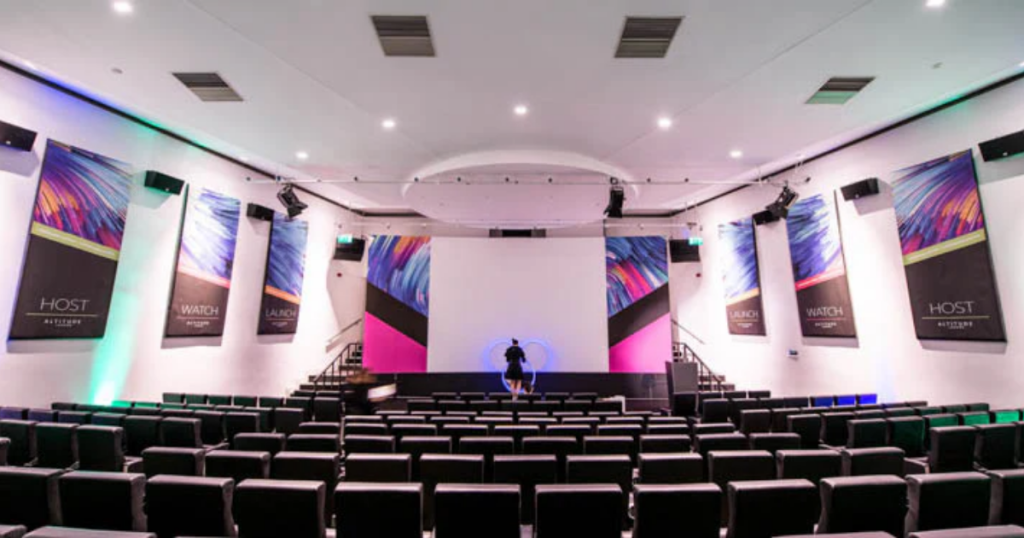 Modern conference hall with large screen, stylish banners, and theater-style seating