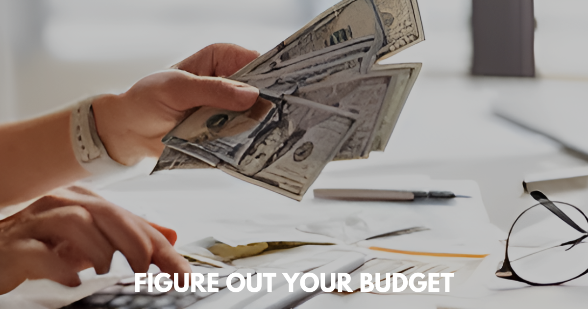 Hands sorting US dollar bills on a cluttered desk with papers, pen, and eyeglasses nearby.