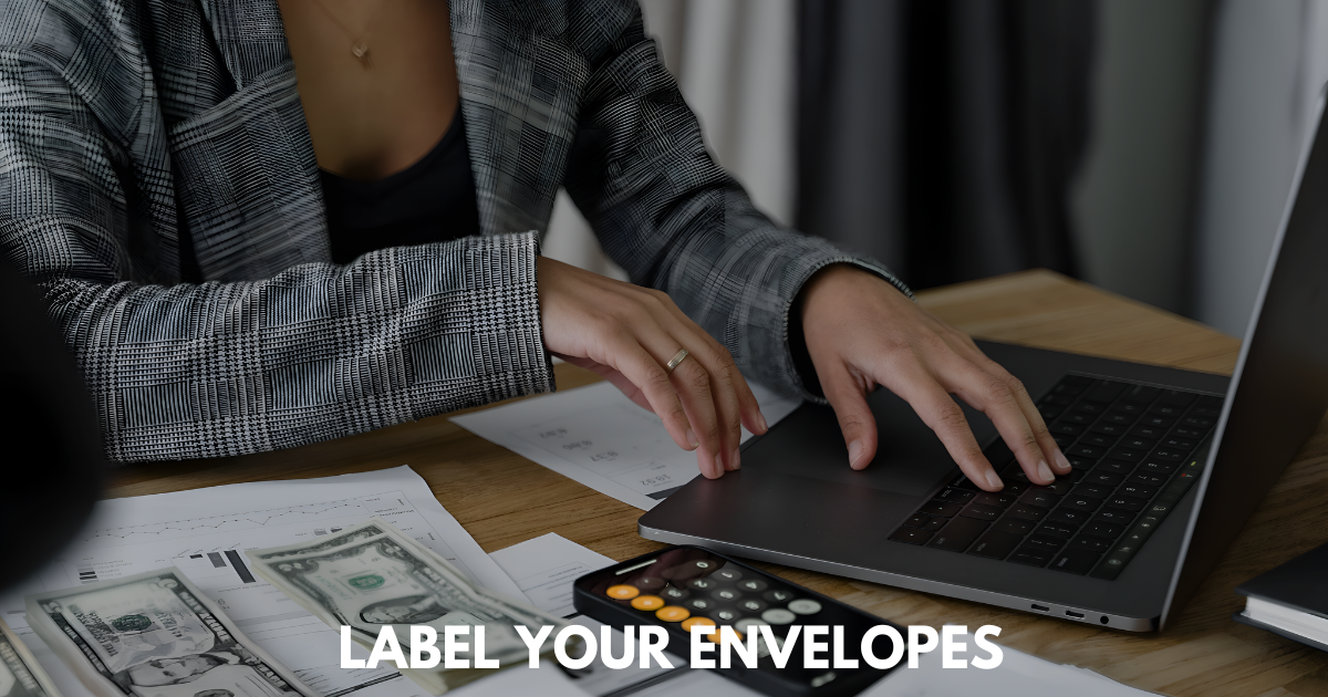 Person in plaid jacket budgeting at laptop with calculator, cash, and documents on desk.