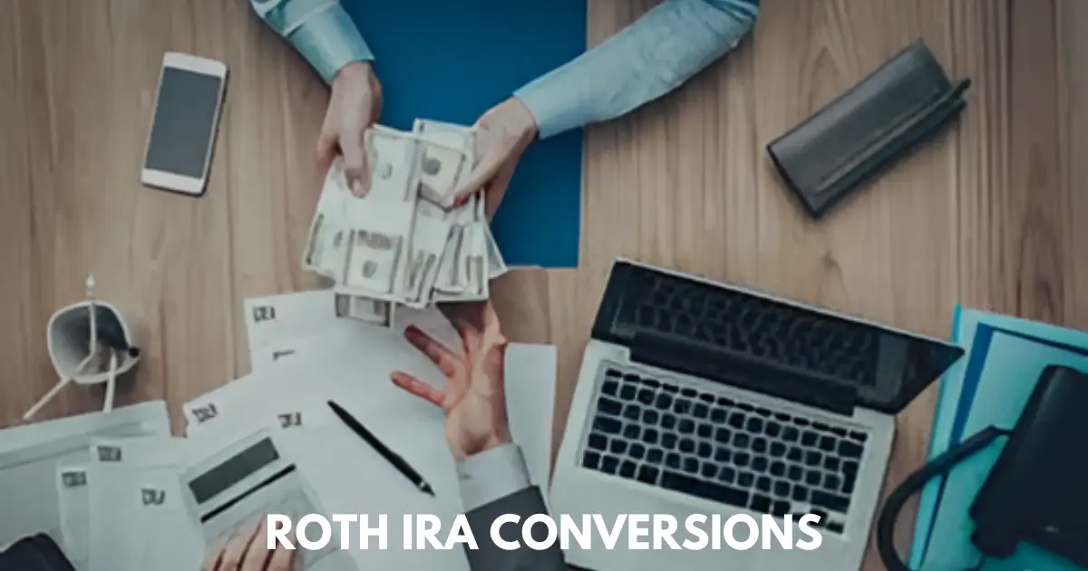 Overhead view of hands exchanging cash over a desk with laptop and documents.